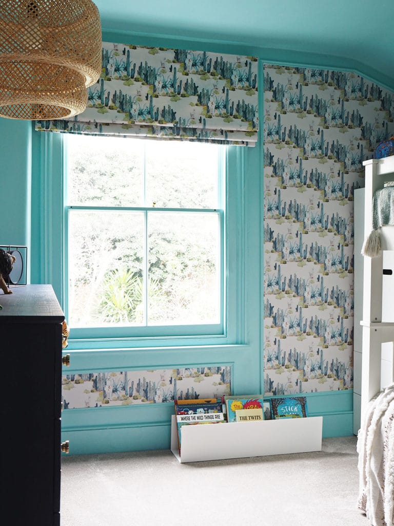 Bright blue bedroom with repeated patter wallpaper, bamboo lampshade and bunk beds