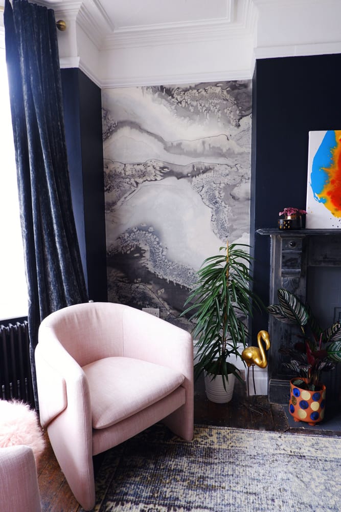 Living room with pink chair and dark blue walls with white and grey marble feature