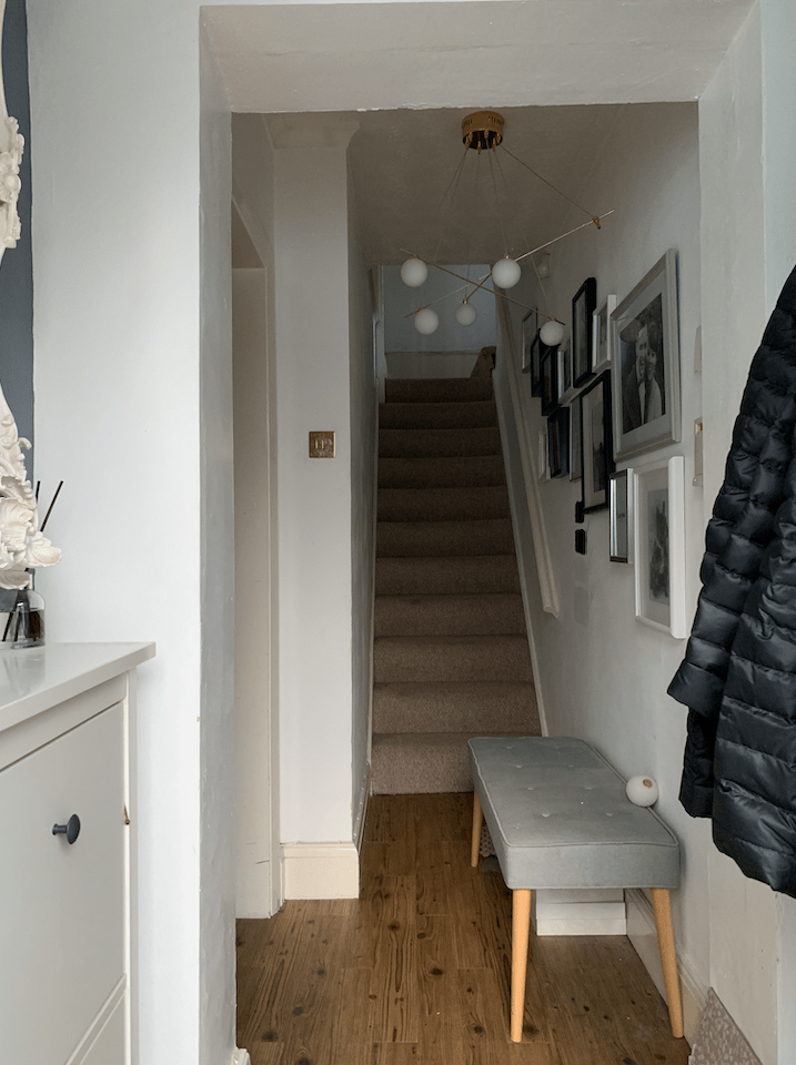 white hallway with wooden floor and grey bench